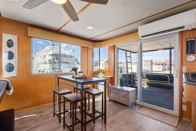 dining area with baseboards, a wall mounted air conditioner, a ceiling fan, and wood finished floors