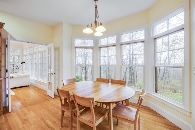 dining area with a notable chandelier, light wood-style flooring, and baseboards