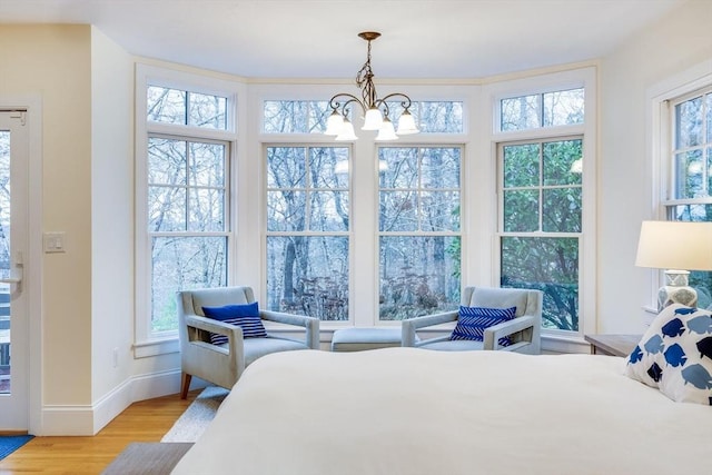 bedroom with light wood-type flooring, baseboards, and an inviting chandelier