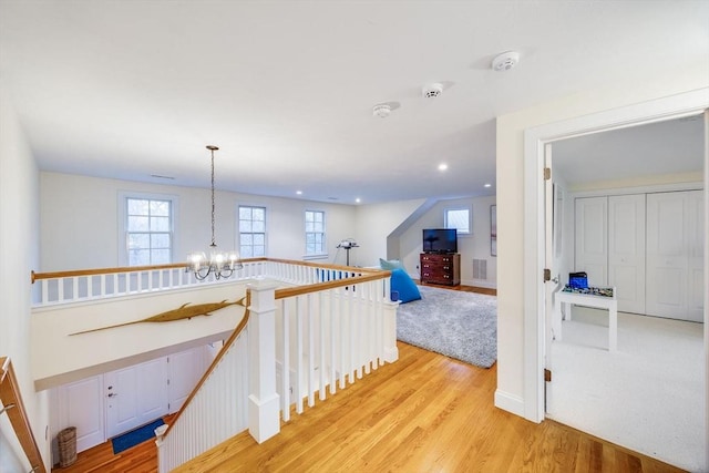 corridor featuring baseboards, an upstairs landing, light wood-type flooring, a notable chandelier, and recessed lighting