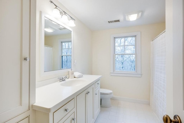 bathroom featuring toilet, vanity, visible vents, and baseboards