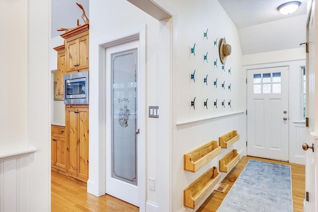 mudroom with a wainscoted wall, visible vents, and light wood finished floors