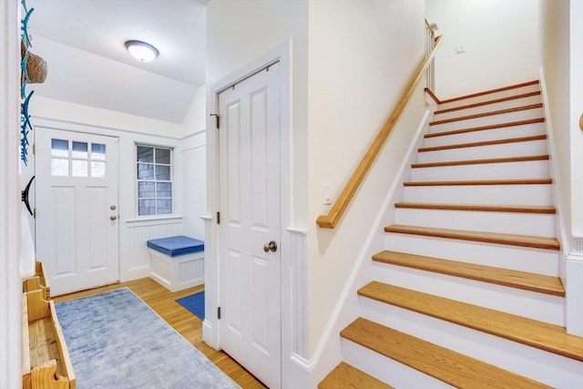 foyer featuring lofted ceiling, light wood finished floors, and stairway