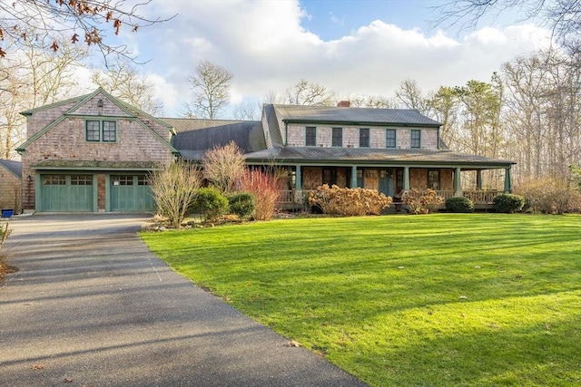 view of front facade with covered porch, driveway, a front lawn, and a chimney