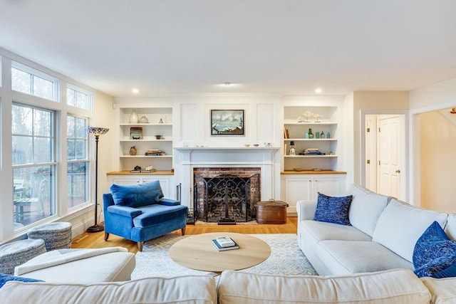 living area featuring built in shelves, a brick fireplace, recessed lighting, and light wood-style floors