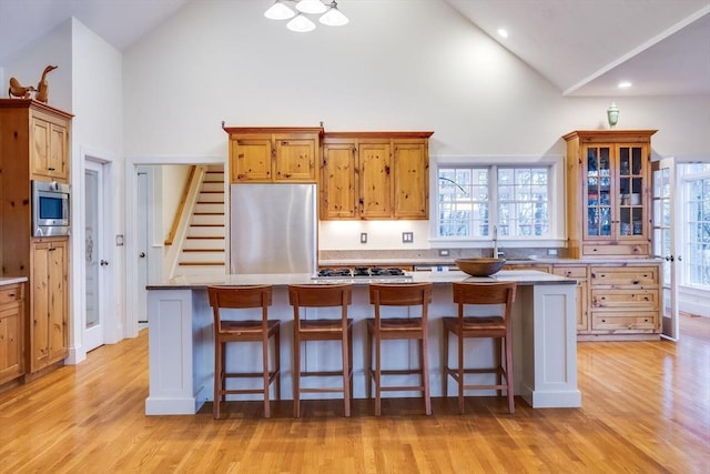 kitchen with light wood-type flooring, a kitchen island, appliances with stainless steel finishes, and a wealth of natural light