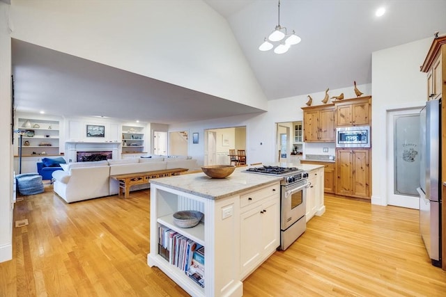 kitchen featuring appliances with stainless steel finishes, a fireplace, light wood finished floors, and a kitchen island