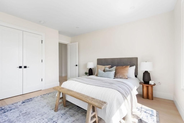bedroom with baseboards, a closet, and light wood-type flooring