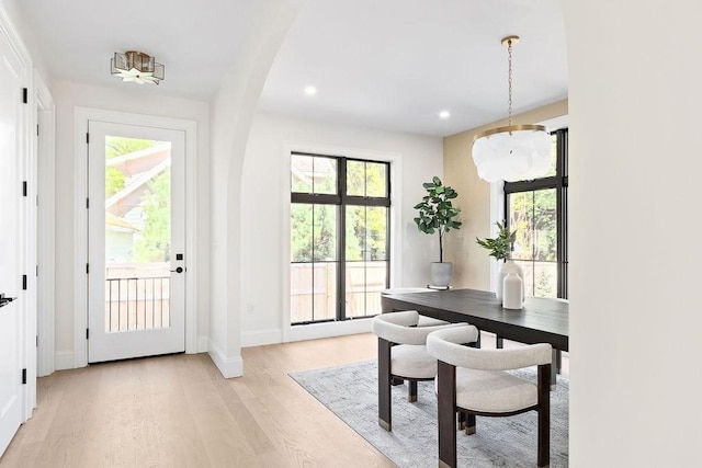doorway with light wood-style flooring, healthy amount of natural light, recessed lighting, baseboards, and arched walkways