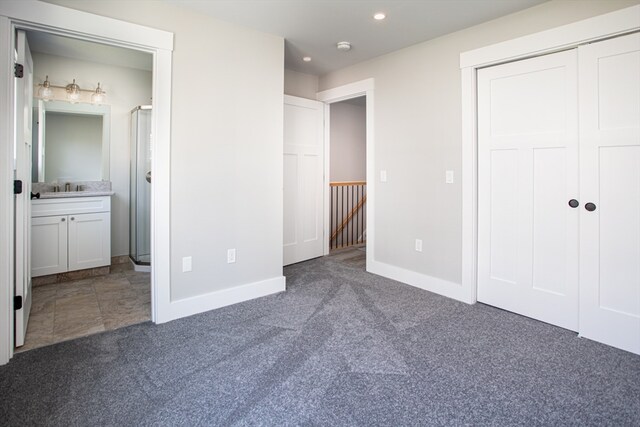 unfurnished bedroom with carpet flooring, ensuite bathroom, and sink