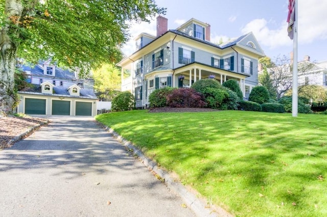 view of front of home with a front lawn, a chimney, and an outdoor structure