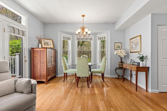dining space with an inviting chandelier, light wood-style flooring, and baseboards
