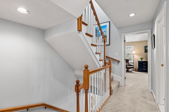 stairway featuring baseboards, carpet, recessed lighting, and a textured ceiling