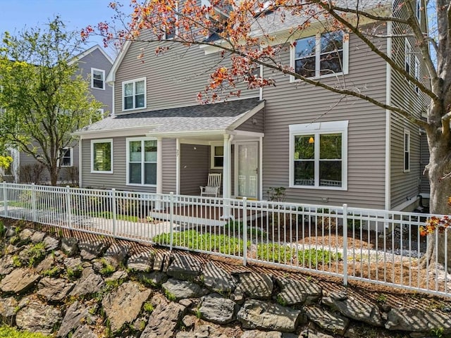 view of front facade with a shingled roof and fence private yard