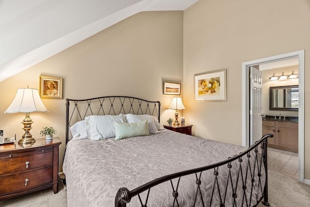 bedroom featuring a sink, lofted ceiling, ensuite bath, and light colored carpet