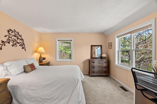 bedroom featuring baseboards, a textured ceiling, visible vents, and light carpet