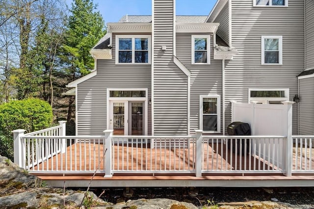 back of property with a wooden deck and a chimney