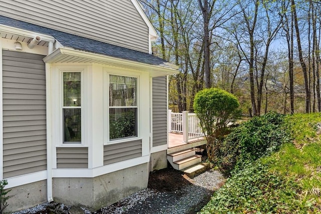 view of home's exterior with a wooden deck and roof with shingles