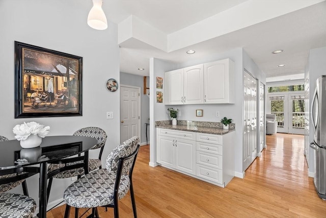 kitchen with freestanding refrigerator, white cabinetry, french doors, and light wood-style floors