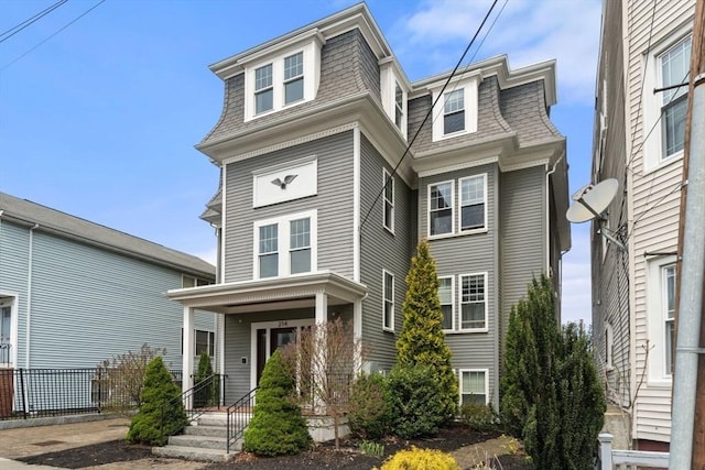 victorian home with roof with shingles and mansard roof
