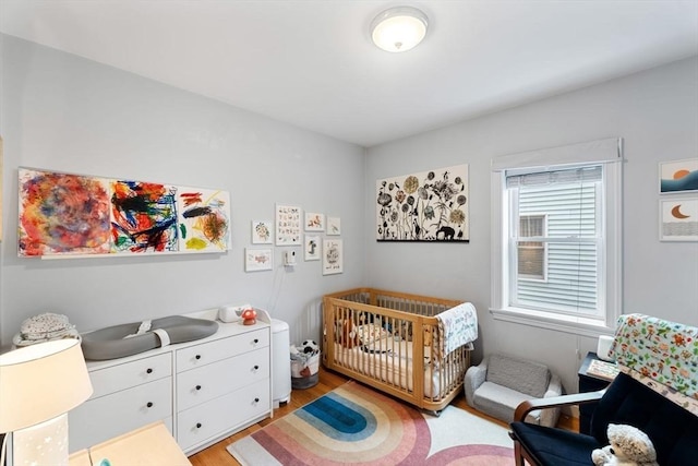 bedroom with light wood finished floors and a nursery area