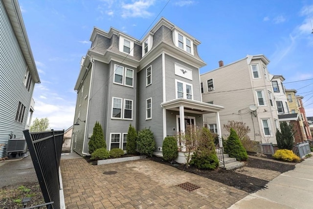 second empire-style home featuring a shingled roof, cooling unit, and mansard roof