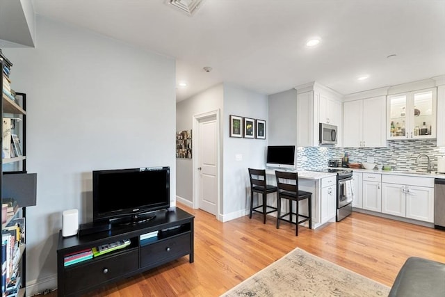 kitchen with light wood-style flooring, light countertops, decorative backsplash, white cabinets, and appliances with stainless steel finishes