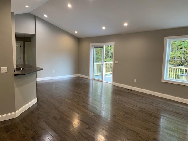 unfurnished living room with a healthy amount of sunlight, dark hardwood / wood-style floors, and vaulted ceiling