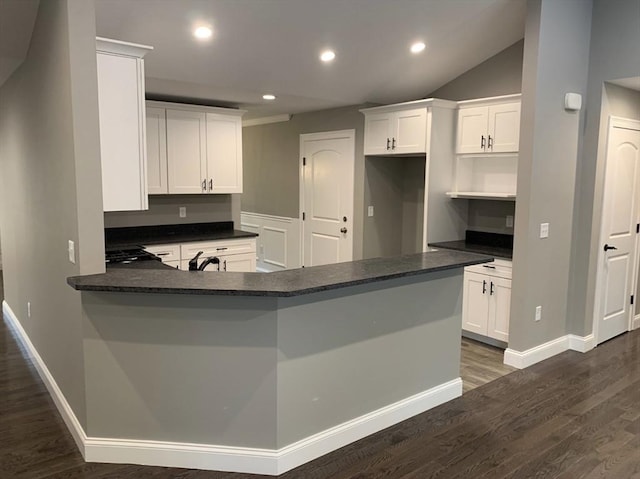 kitchen featuring lofted ceiling, sink, white cabinets, kitchen peninsula, and dark wood-type flooring