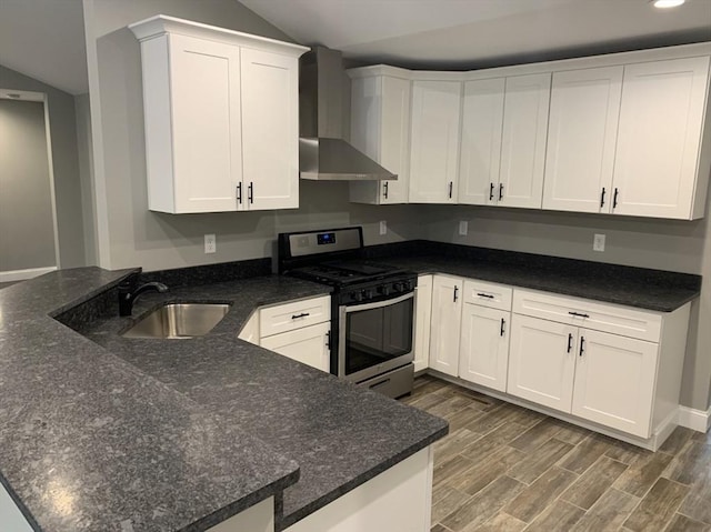 kitchen with white cabinetry, stainless steel range with gas cooktop, kitchen peninsula, and wall chimney exhaust hood