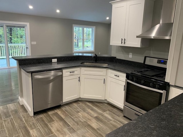 kitchen with white cabinetry, wall chimney range hood, sink, and appliances with stainless steel finishes