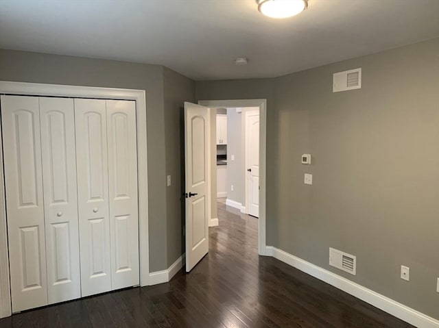 unfurnished bedroom with dark hardwood / wood-style flooring and a closet