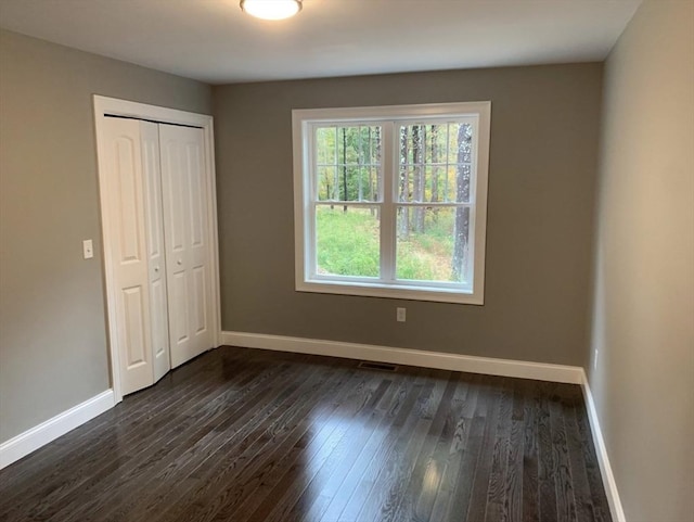 unfurnished bedroom featuring dark hardwood / wood-style flooring and a closet