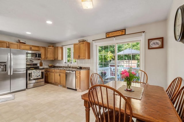 kitchen featuring dark countertops, light floors, recessed lighting, appliances with stainless steel finishes, and a sink