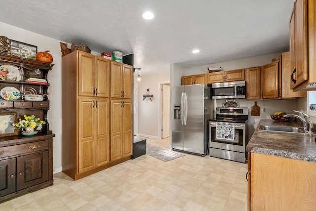 kitchen with a sink, dark countertops, recessed lighting, stainless steel appliances, and light floors