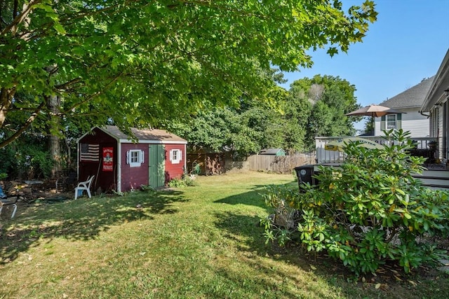 view of yard featuring a wooden deck, an outbuilding, a storage shed, and fence