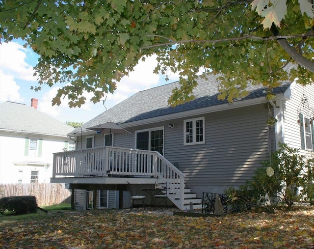 rear view of house featuring a deck and fence