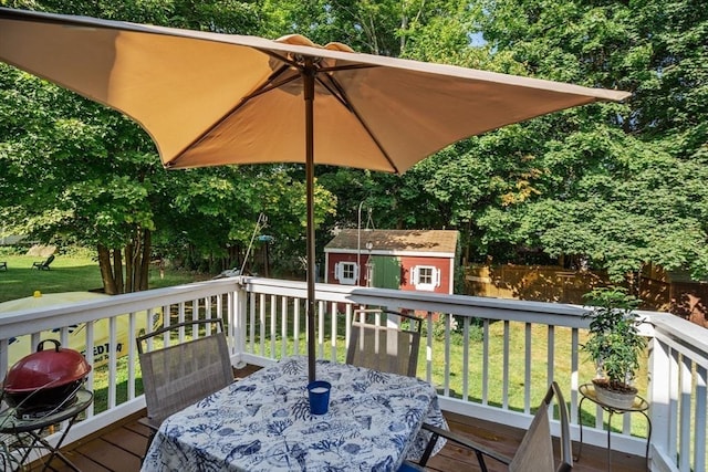 deck featuring an outbuilding, outdoor dining space, a yard, and area for grilling