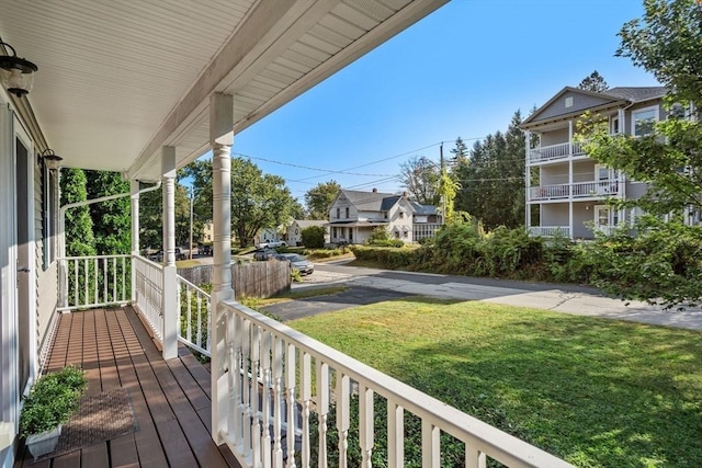 wooden terrace featuring a porch, a yard, and a residential view