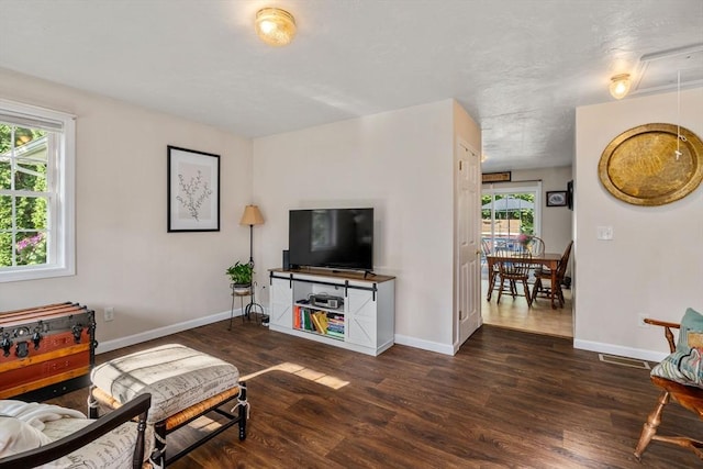 living room with visible vents, baseboards, and wood finished floors