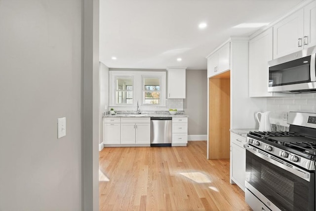 kitchen with light stone countertops, white cabinets, stainless steel appliances, decorative backsplash, and sink