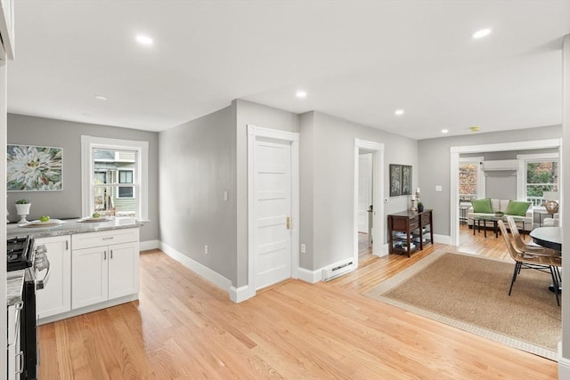 kitchen featuring white cabinetry, light hardwood / wood-style flooring, a wealth of natural light, and stainless steel gas range oven