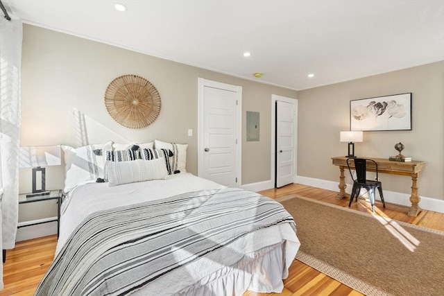 bedroom featuring electric panel, a baseboard radiator, and hardwood / wood-style floors