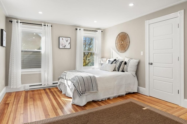 bedroom featuring a baseboard heating unit, ornamental molding, and hardwood / wood-style flooring