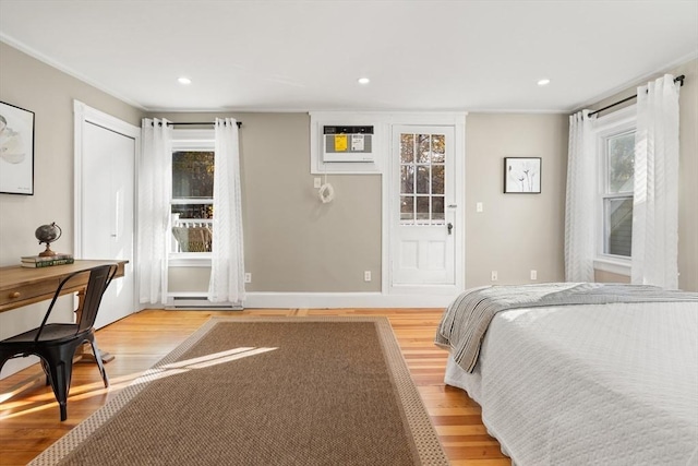 bedroom featuring light wood-type flooring, a baseboard heating unit, and a wall unit AC