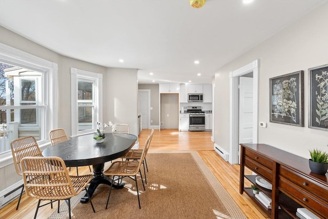 dining space with a baseboard heating unit and light hardwood / wood-style flooring