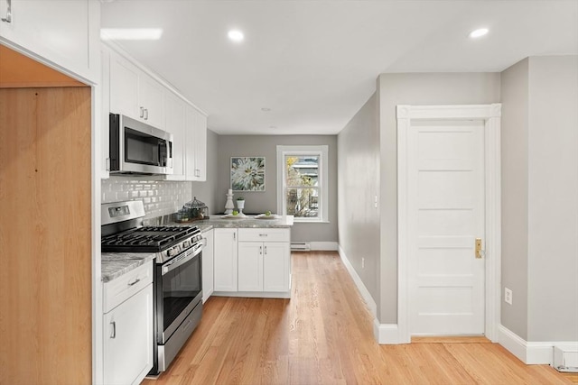 kitchen with light stone countertops, appliances with stainless steel finishes, white cabinetry, light hardwood / wood-style floors, and backsplash