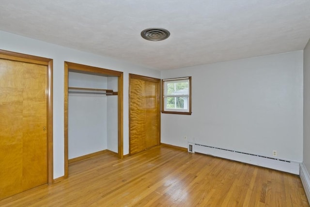 13 Louise Ave, Chicopee, MA 01013 - unfurnished bedroom with a baseboard heating unit, light wood-style flooring, and multiple closets