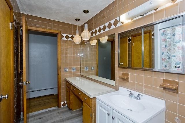 13 Louise Ave, Chicopee, MA 01013 - full bathroom with a baseboard heating unit, tile walls, wood finished floors, vanity, and backsplash