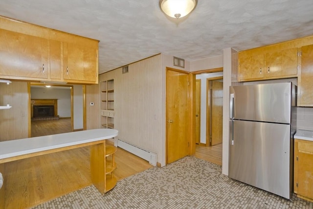 13 Louise Ave, Chicopee, MA 01013 - kitchen with freestanding refrigerator, baseboard heating, light countertops, a fireplace with raised hearth, and wooden walls